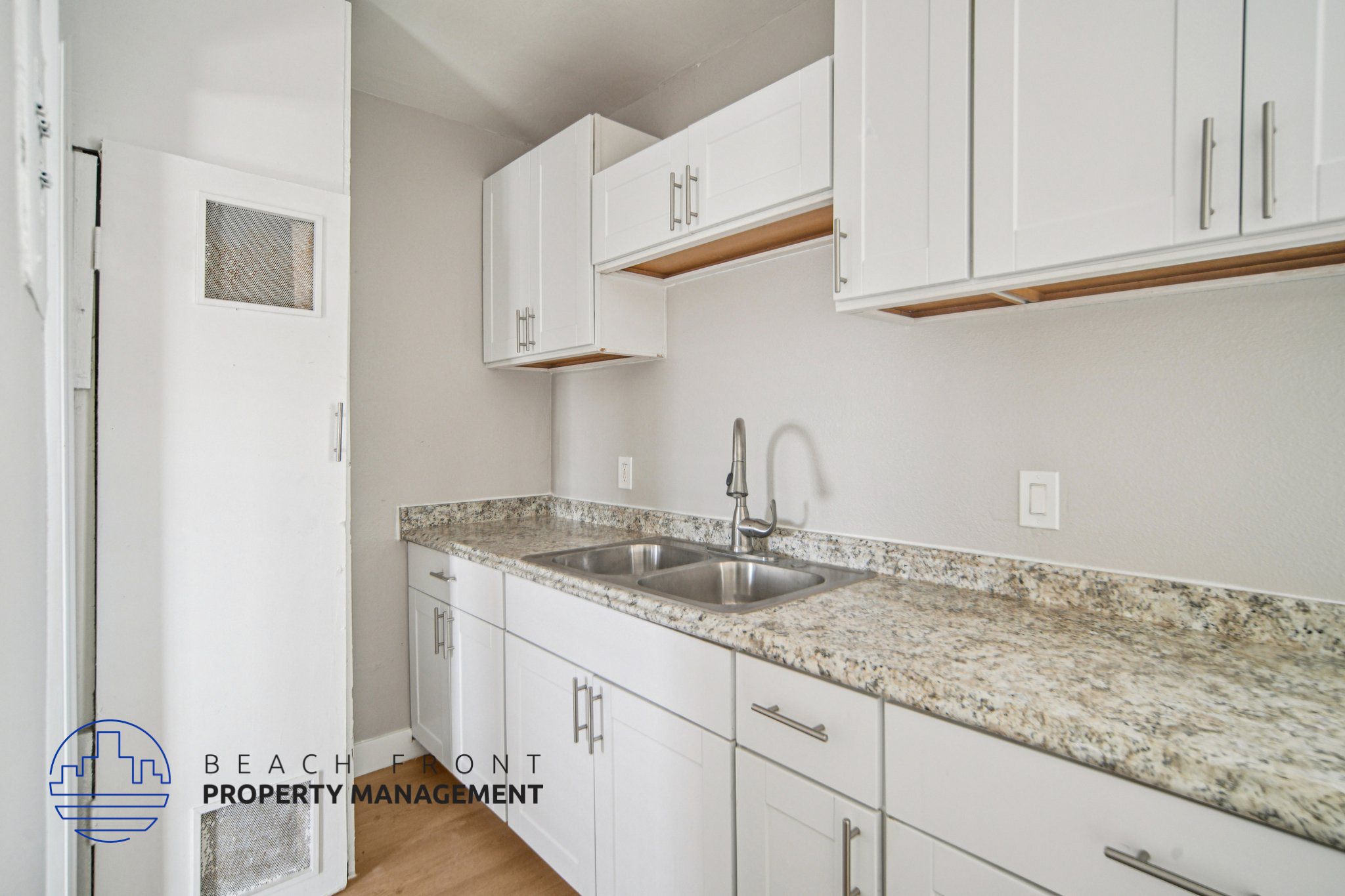 A kitchen with white cabinets and a granite countertop.